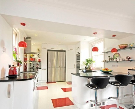 Biela kuchyňa s červenými prvkami.