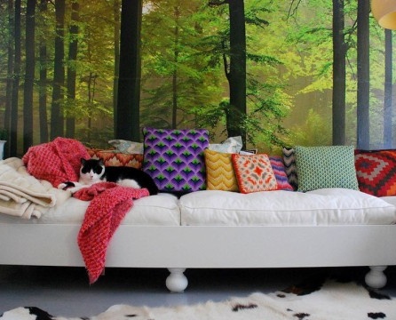 Λευκός καναπές με πολύχρωμα μαξιλάρια υπό ταπετσαρία τοπίου