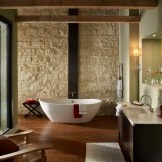 Interiér koupelny s jedinou stěnou zdobené světlým kamenem