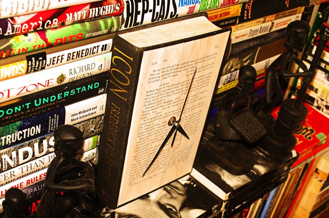 A clock-book stands between the statuettes