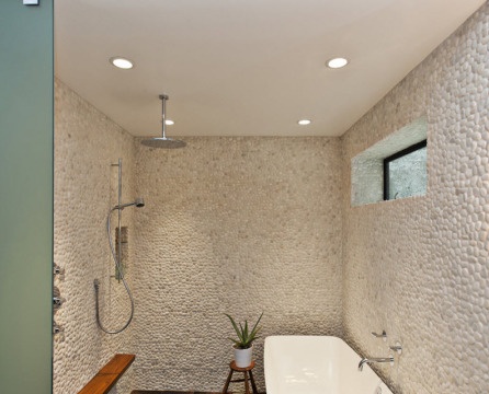 חלוקי נחל על הקיר בחדר האמבטיה, מכוסים בצבע לבן