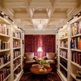 Minkšti patogūs foteliai, jaukus kilimas ir žurnalinis staliukas nuostabiai papildo bibliotekos interjerą