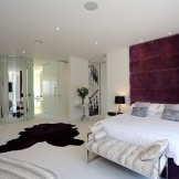 Baltas kilimas ir purpurinė siena miegamajame