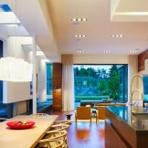 Elegant chandelier and spotlights around the perimeter of the kitchen and living areas