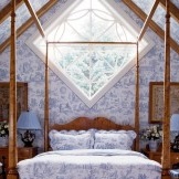 Textiles y almohadas en la cama repiten el patrón de papel tapiz en la pared