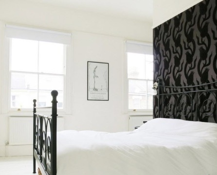 غرفة نوم بيضاء اللون مع جدار مشرق