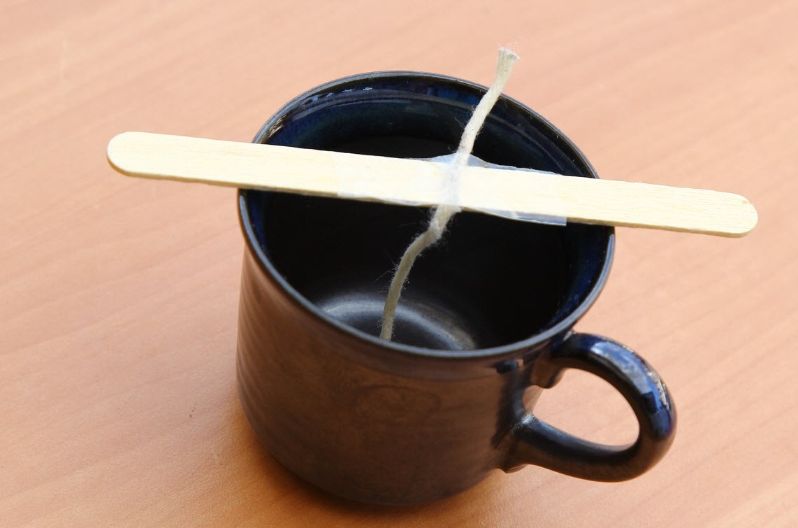 Palo de madera con una mecha en una taza