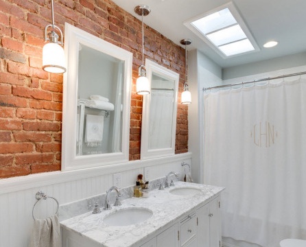 Twee witte spiegels op een bakstenen muur in de badkamer