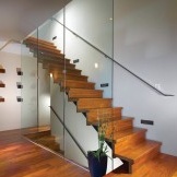 Escalera de madera con barandas de vidrio.