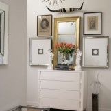 مرآة على خزانة ذات أدراج بيضاء في الرواق