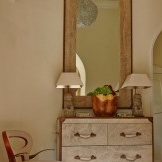 Mirror in an old frame over a white chest of drawers
