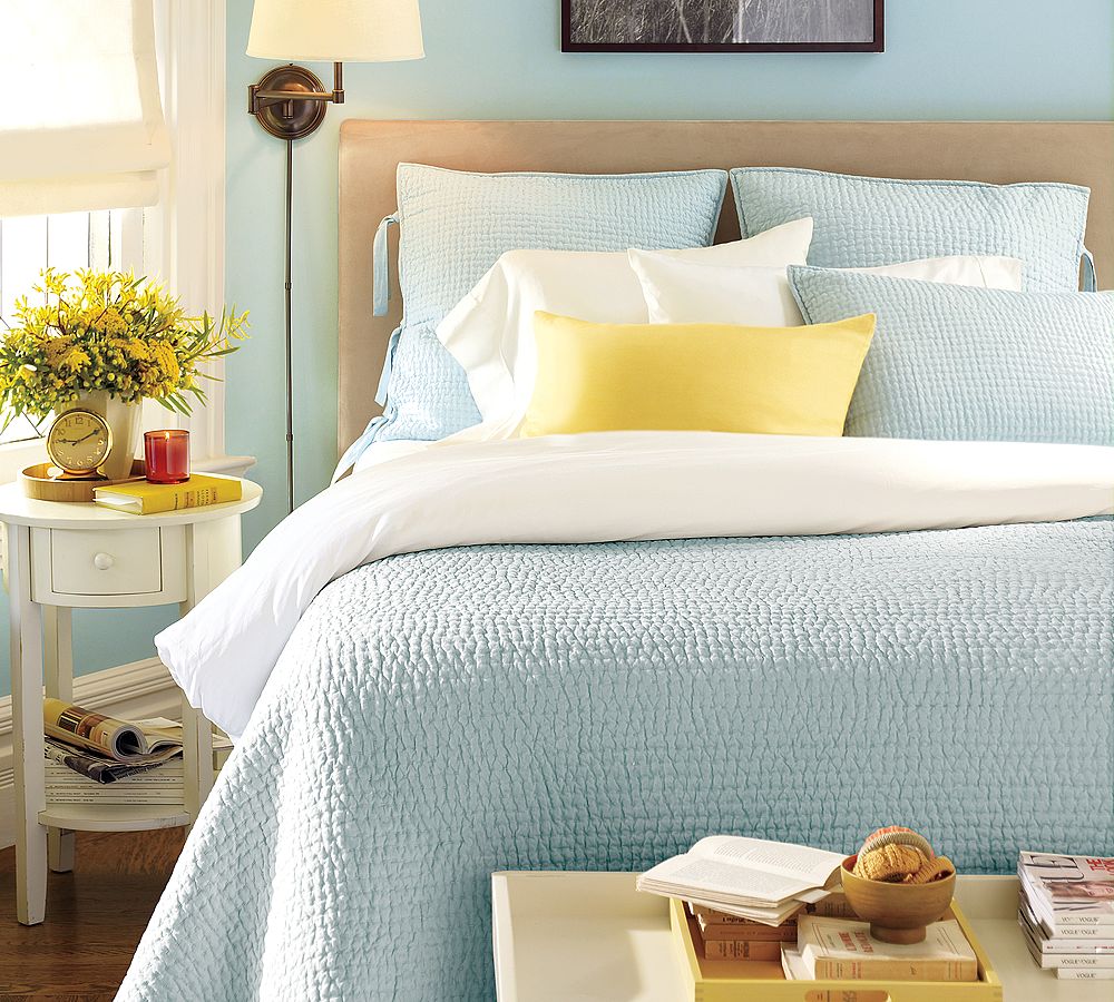 Μπλε κουβέρτα, μαξιλάρια και τοίχοι στο υπνοδωμάτιο