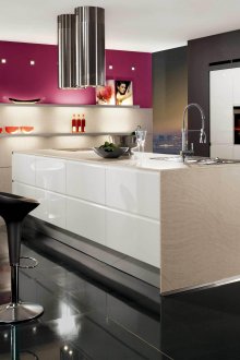 Cocina minimalista en blanco y negro con una isla con un acento rosa en la pared.