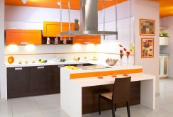 Πορτοκαλί, λευκά και καφέ χρώματα στο εσωτερικό της κουζίνας με μια χερσόνησο