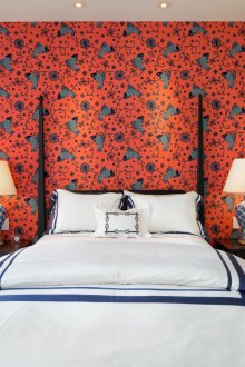 Papel tapiz floral a un lado de la cabecera de la cama.