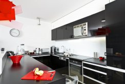 Μαύρη και λευκή γυαλιστερή κουζίνα με κόκκινες προθέσεις