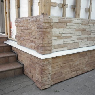 Frente a la casa con paneles de fachada de piedra.