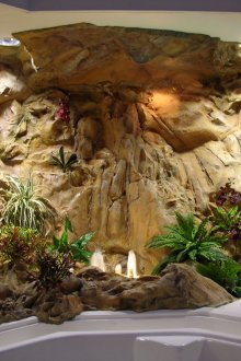 Dekorativer Wasserfall und künstliche Pflanzen im Badezimmerinnenraum