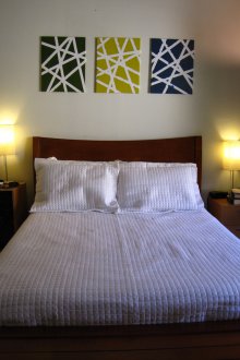 Pinturas com padrão geométrico sobre a cama no quarto