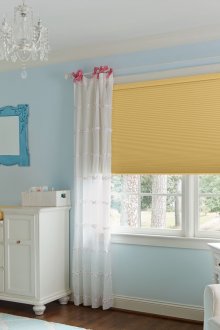 Çocuk odasında sarı güneşlikler ve açık beyaz perdeler