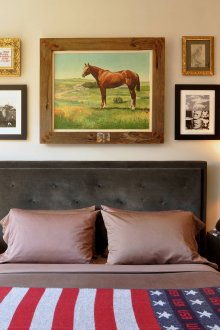 Uma pintura com um cavalo e outras pinturas acima da cabeceira da cama
