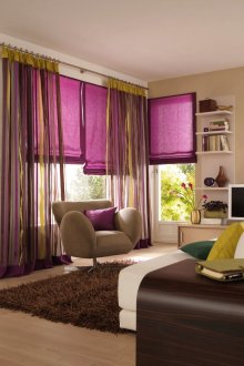 A combination of pink Roman curtains and multi-colored ordinary in the interior of the living room